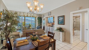 Un comedor con vistas al océano, una cocina con televisor de pantalla plana y un baño con bañera.