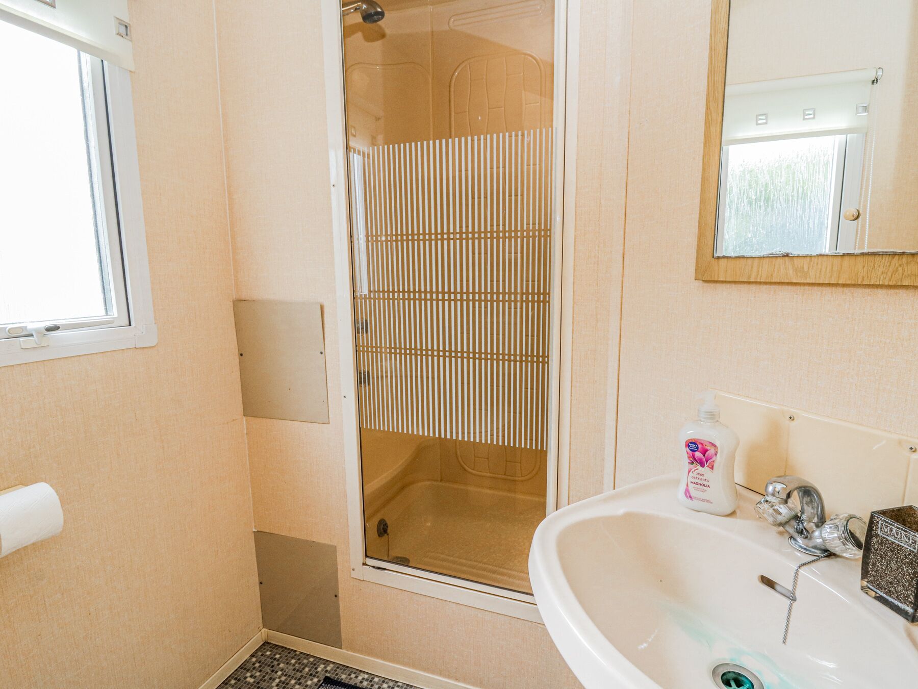 Un baño con ducha, lavamanos y espejo.