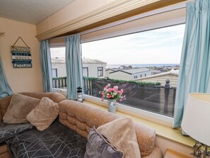Un salon chaleureux avec une grande fenêtre, un canapé et un panneau décoratif accroché au mur.
