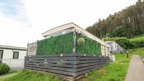 Un edificio moderno con un muro verde y una terraza de madera.
