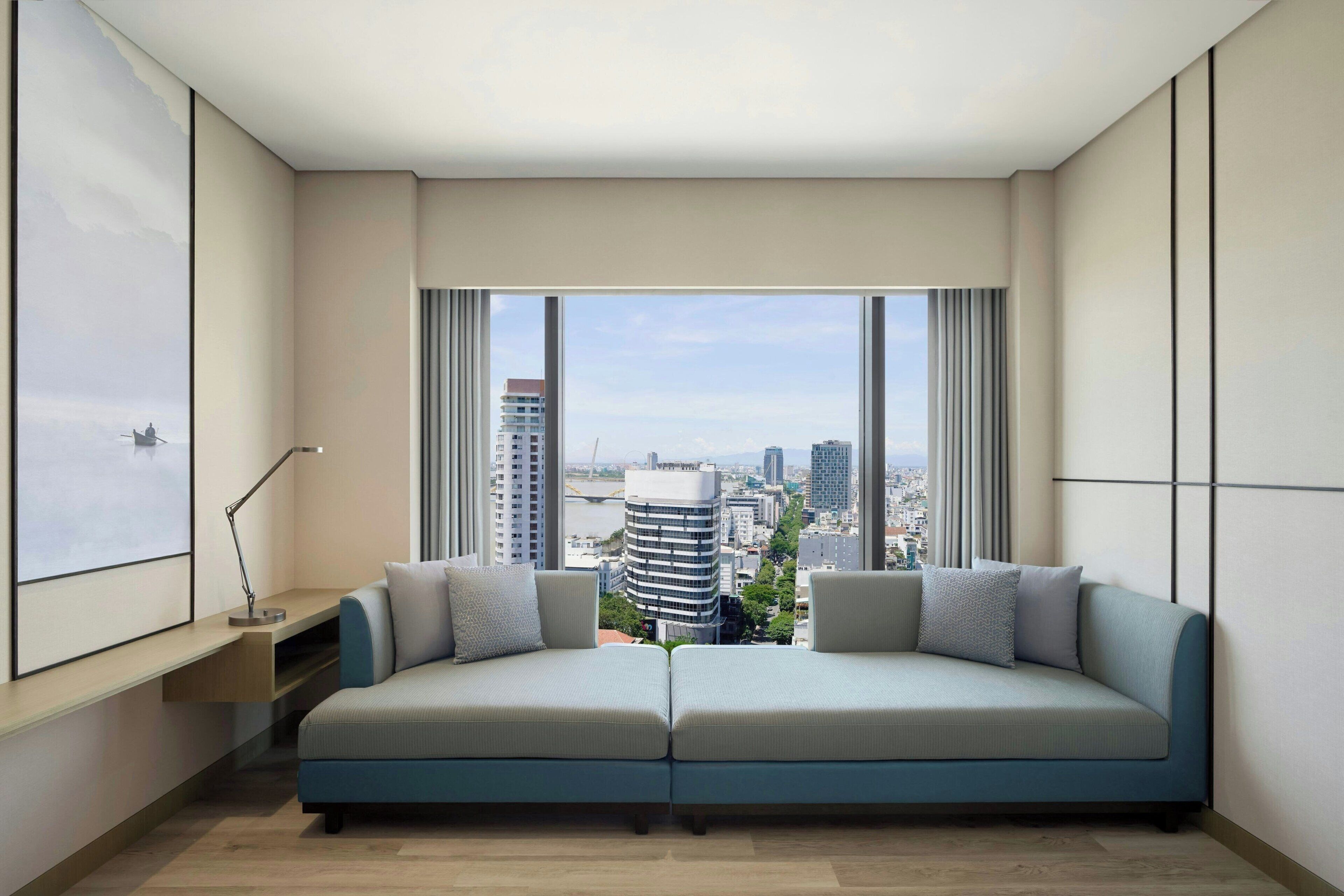 A modern living room with a sofa facing a large window overlooking a cityscape.
