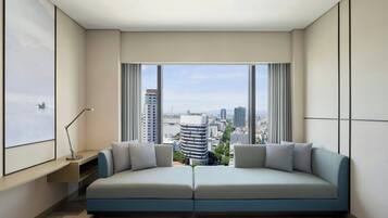 A modern living room with a sofa facing a large window overlooking a cityscape.