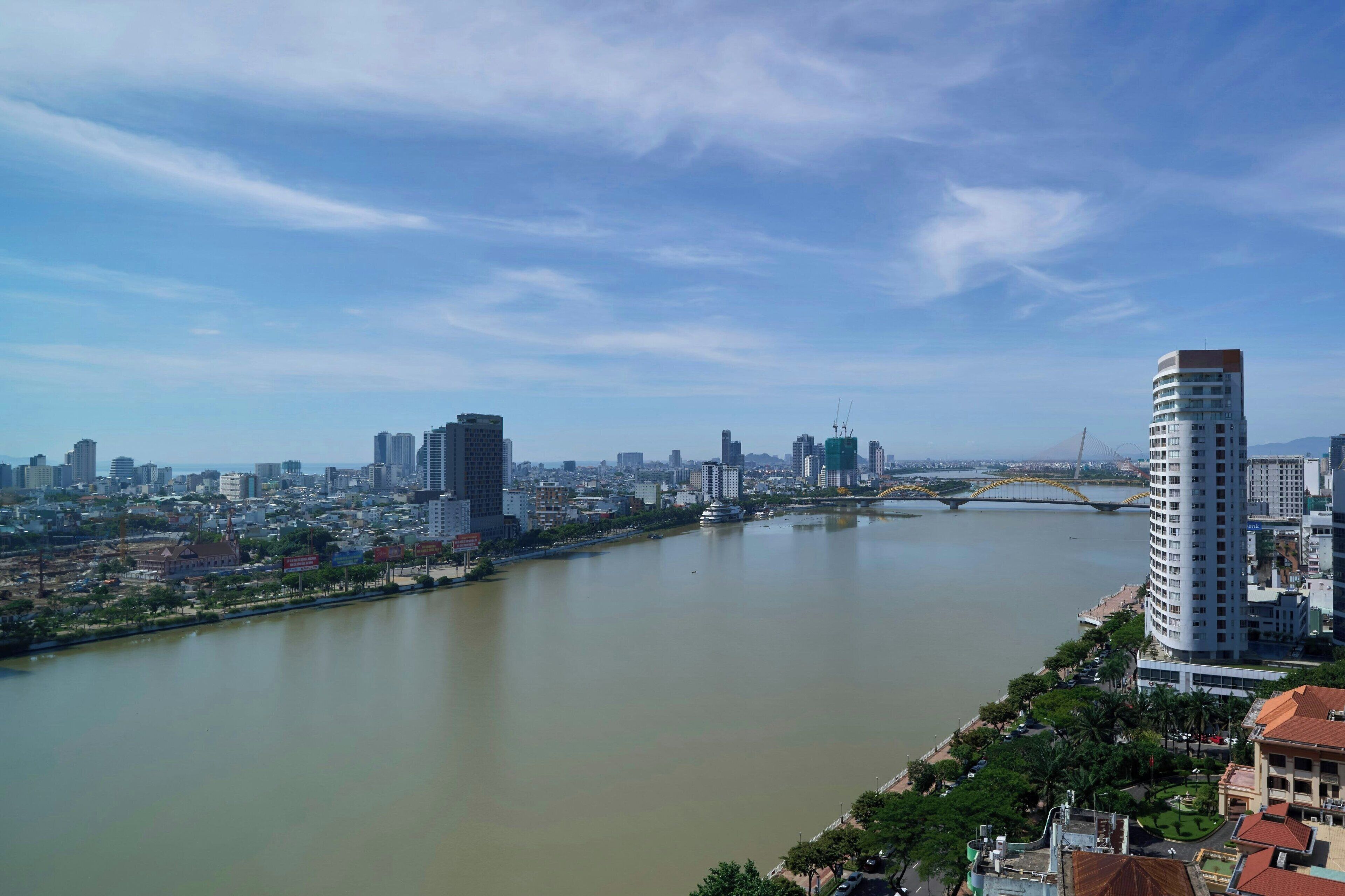 A river with a bridge, a city skyline, and a tall building with a curved top.