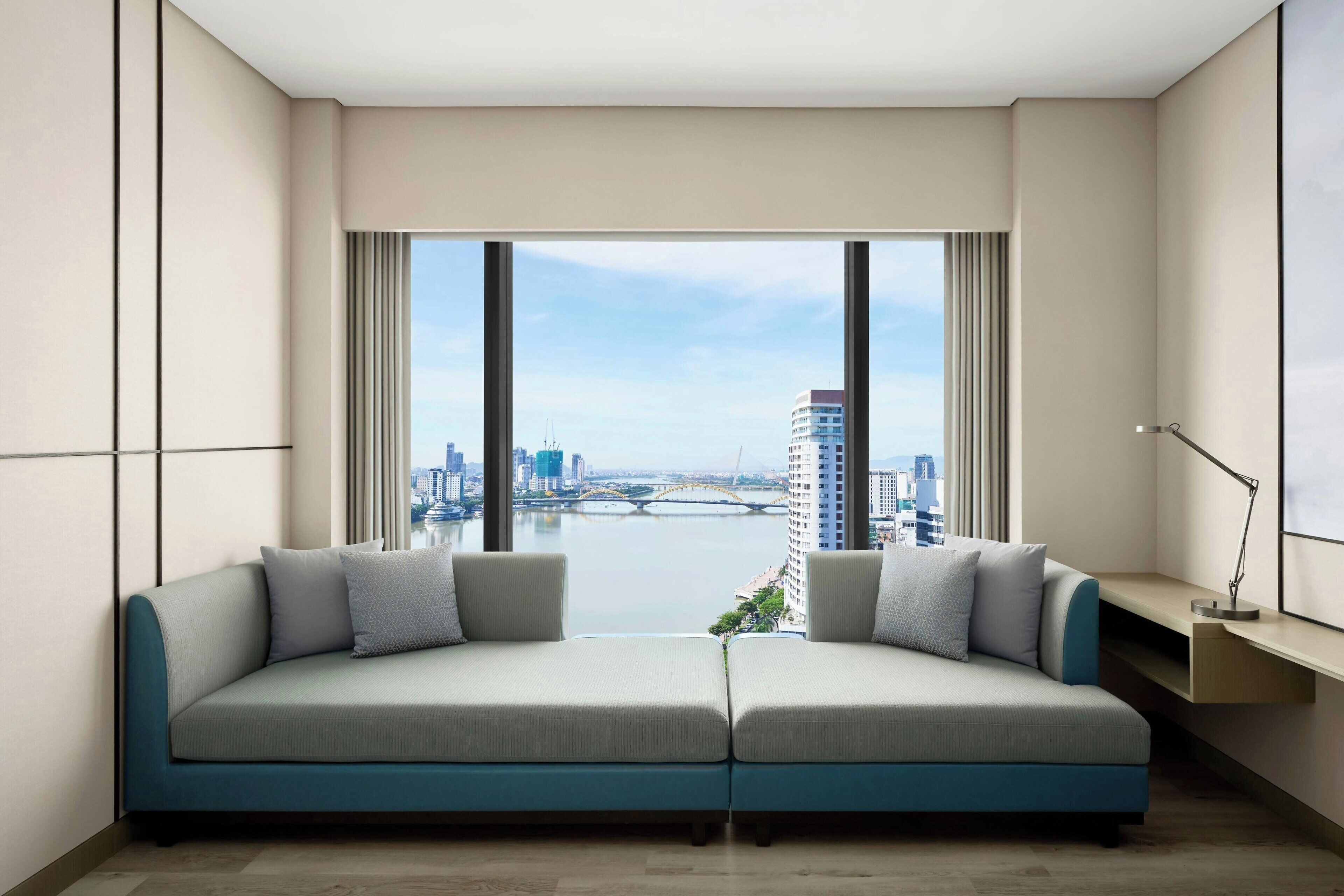 A modern living room with a sofa facing a large window overlooking a cityscape.