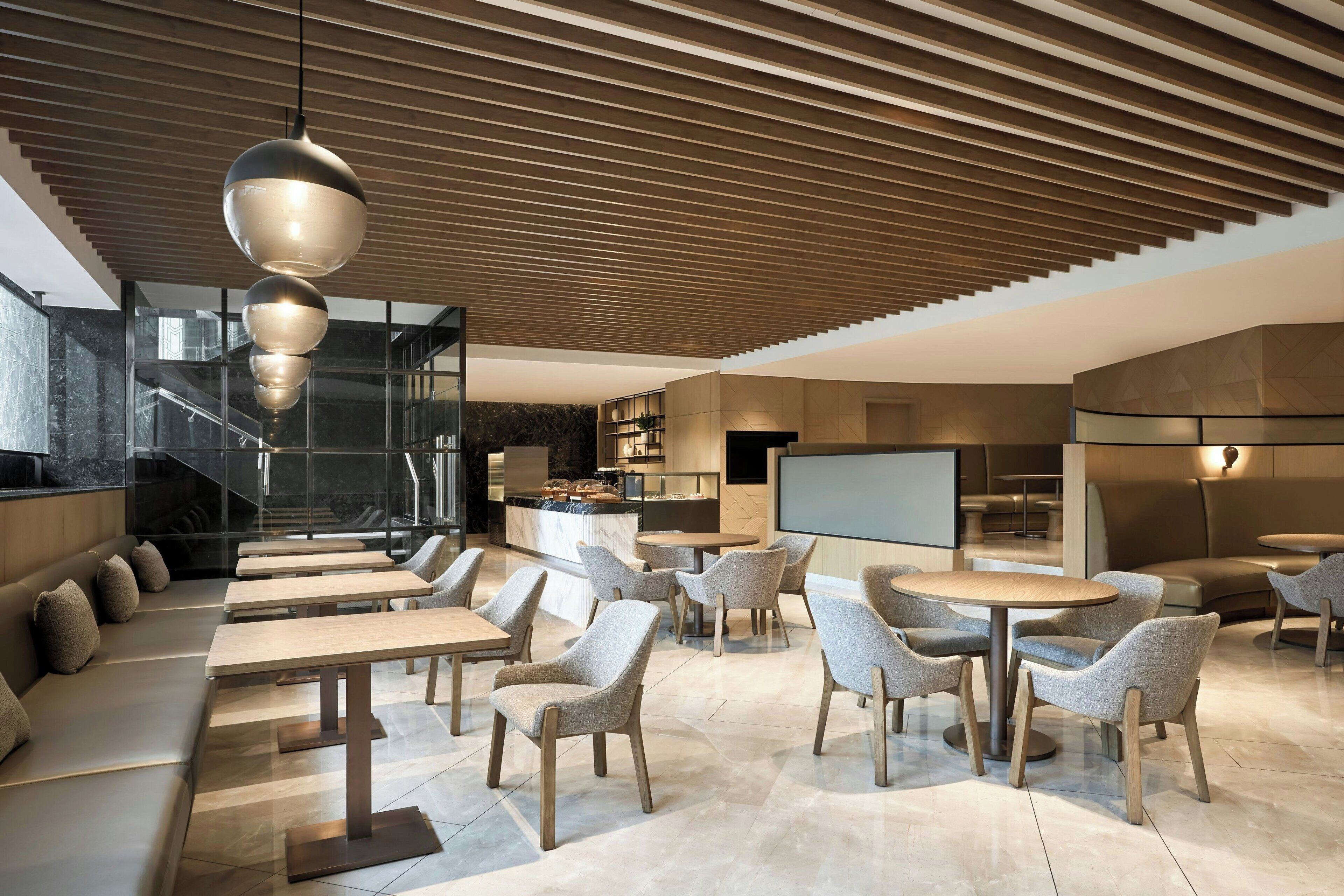 A modern interior with seating areas, a kitchen, and a large screen.