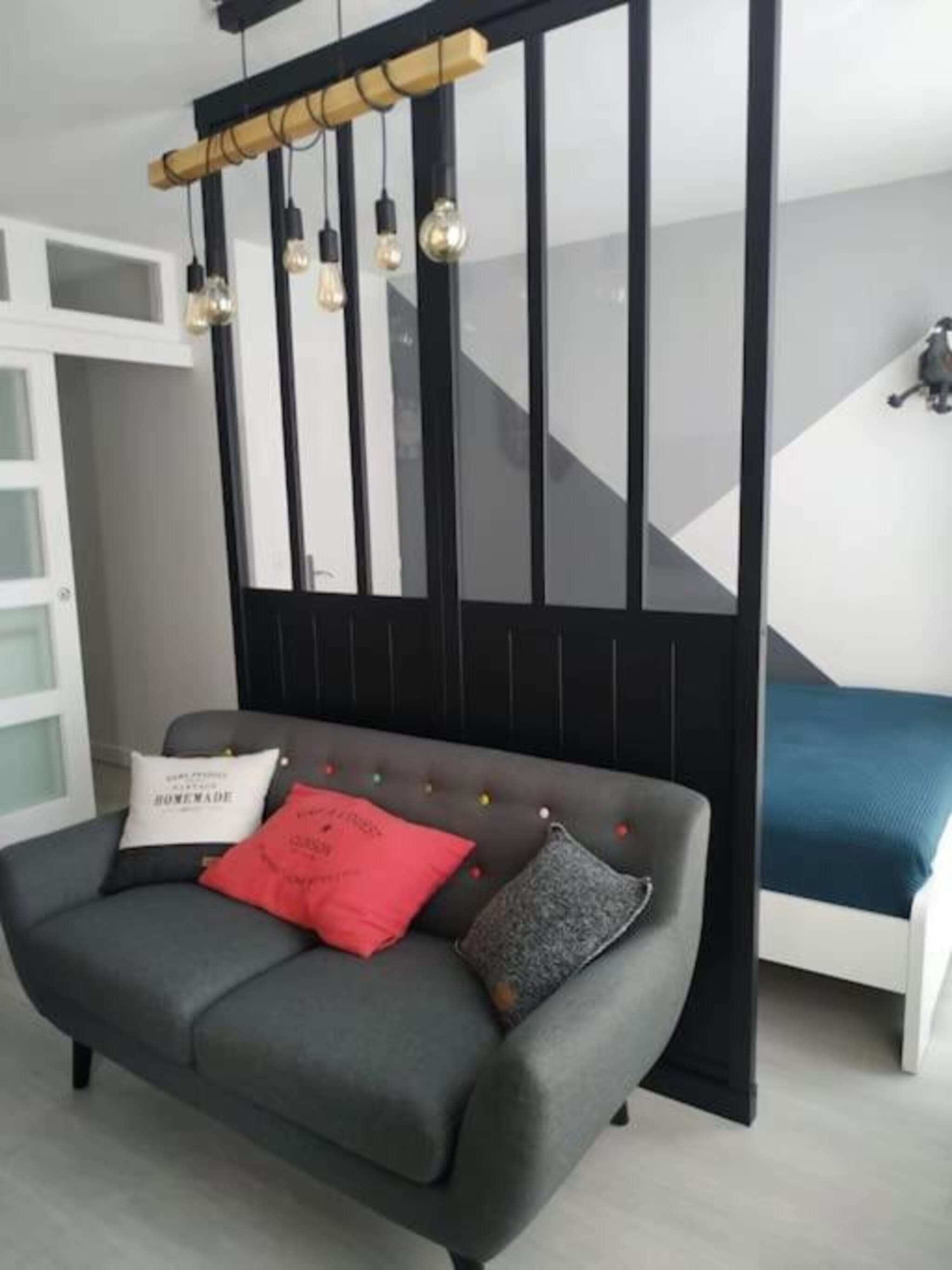 En moderne stue med en grå sofa, en væg i sort og et geometrisk mønster på væggen.