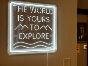 A neon sign with the text "THE WORLD IS YOURS TO EXPLORE" on a wall.