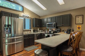 A modern kitchen with stainless steel appliances, dark cabinetry, and a large island.