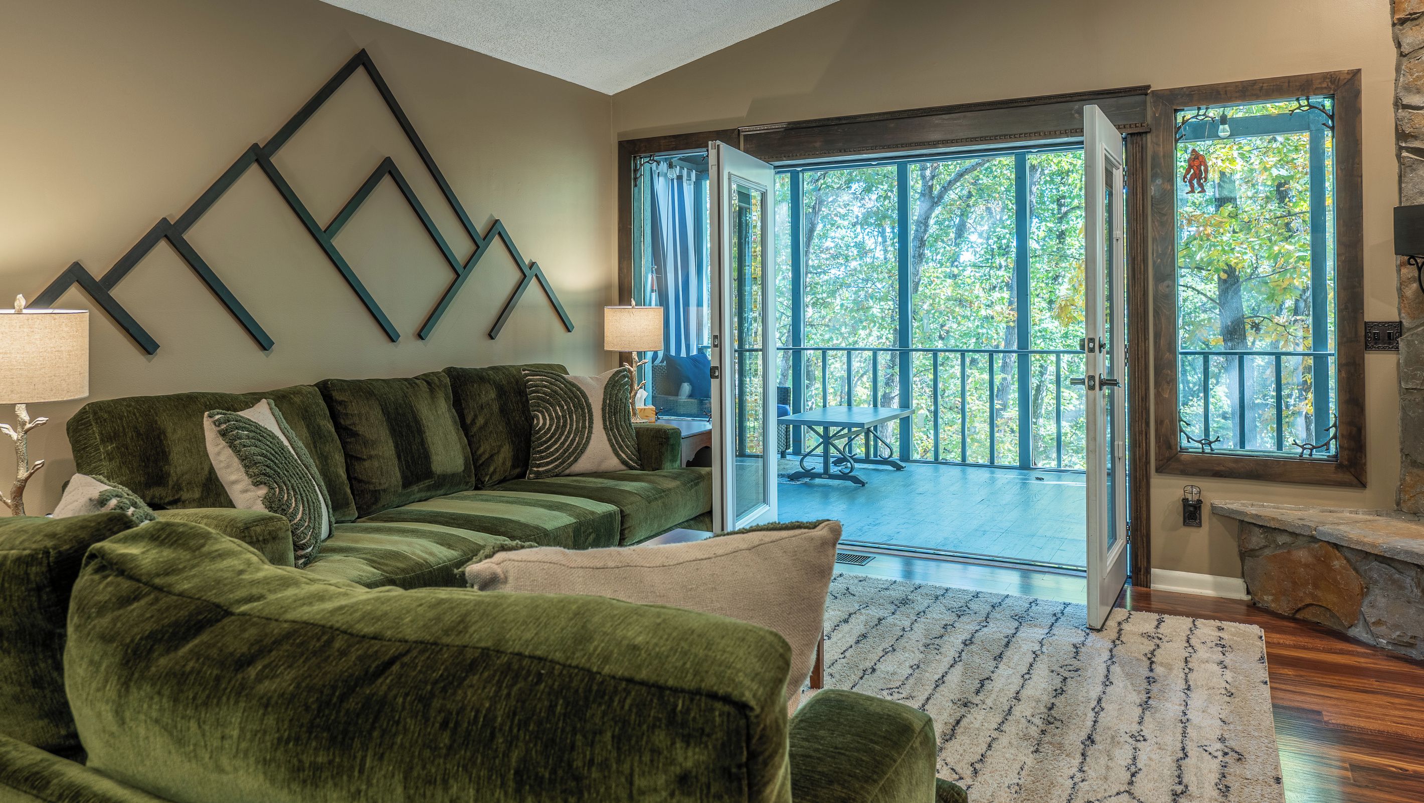 A living room with a sectional sofa, a lamp, and a view through a glass door to an outdoor patio.