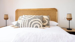 A neatly made bed with a woven headboard, two bedside lamps, and a white wall. - Palm & Sea apartment (Los Alcazares)