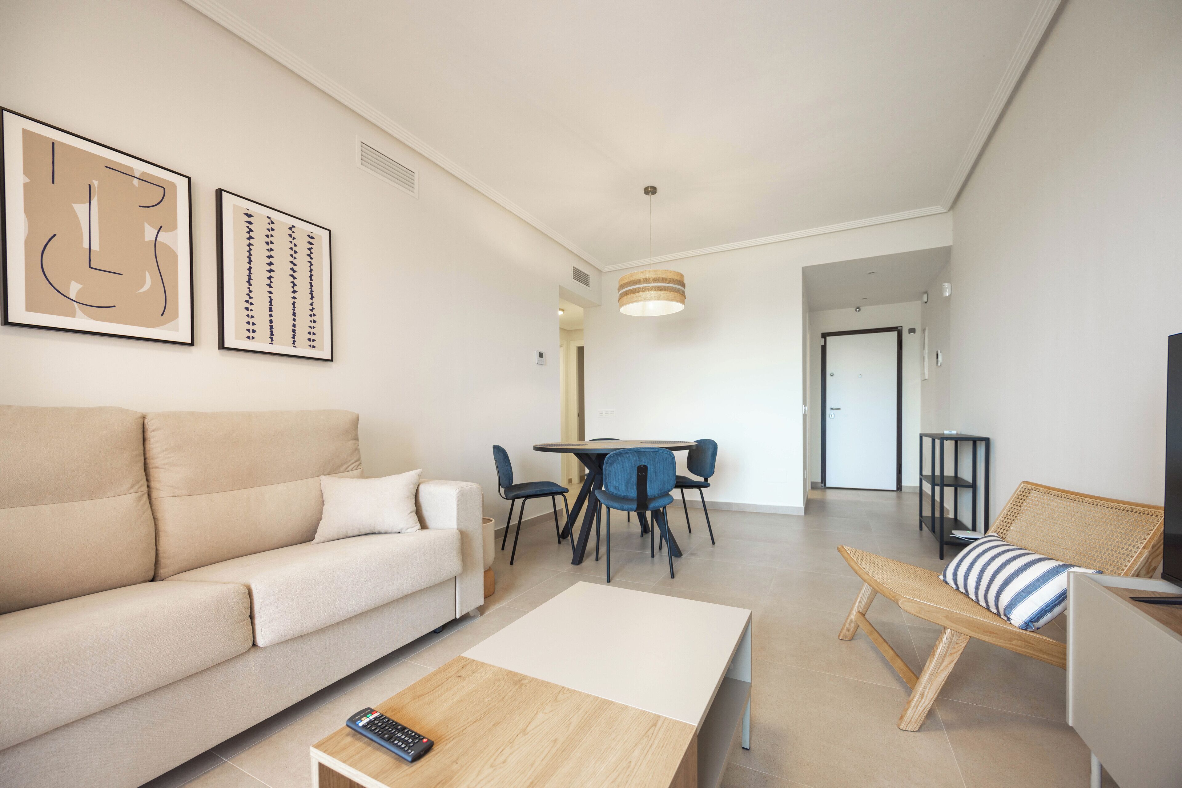 A modern living room with a sofa, coffee table, and a dining area with chairs and a table.