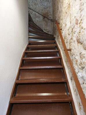 A staircase with wooden steps and metal railings in a stone-walled corridor. - Fortezza Nest - Old Town Rethymno (Rethymno)