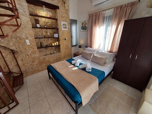 A bedroom with a bed, a wardrobe, a shelf with decorative items, and a wall-mounted air conditioner. - Fortezza Nest - Old Town Rethymno (Rethymno)
