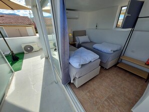 A compact room with two beds, a small table, and a window.