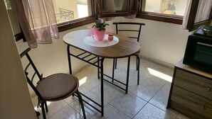 A small dining area with a round table, two chairs, a potted plant, and a cabinet. - Fortezza Nest - Old Town Rethymno (Rethymno)