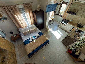 A hotel room with a bed, a TV, a desk, a kitchenette, and a bathroom. - Fortezza Nest - Old Town Rethymno (Rethymno)