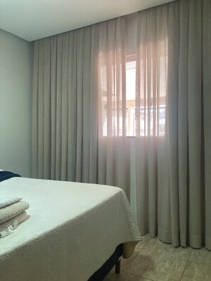 Una habitación de hotel con cama, cortinas y ventana.