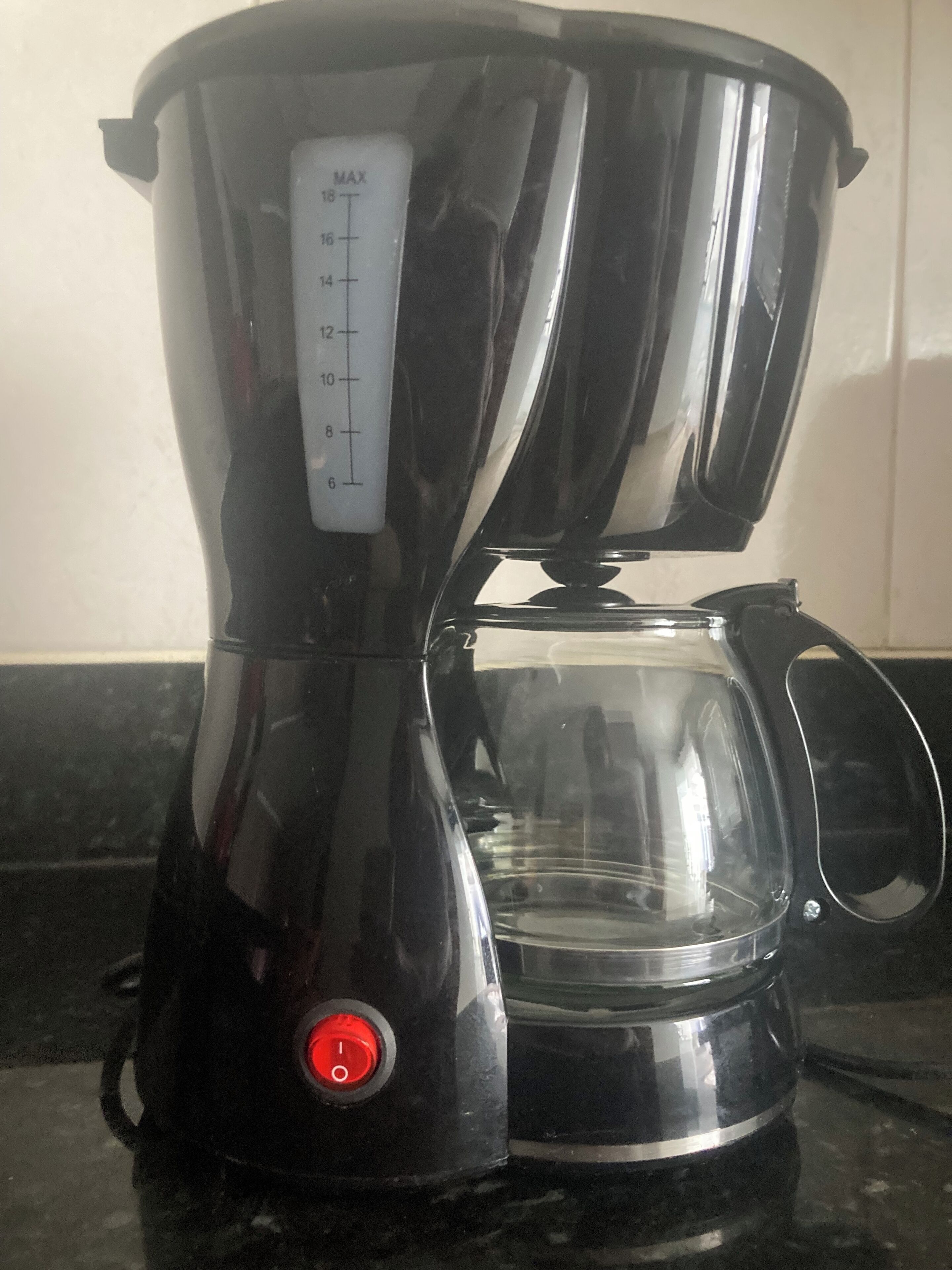 Una cafetera negra con un depósito de agua transparente y una balanza graduada con medidas.