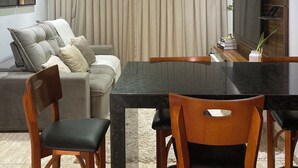 Un salon moderne avec un canapé, une table à manger et des chaises. On y trouve également un téléviseur et une plante posée sur la table.