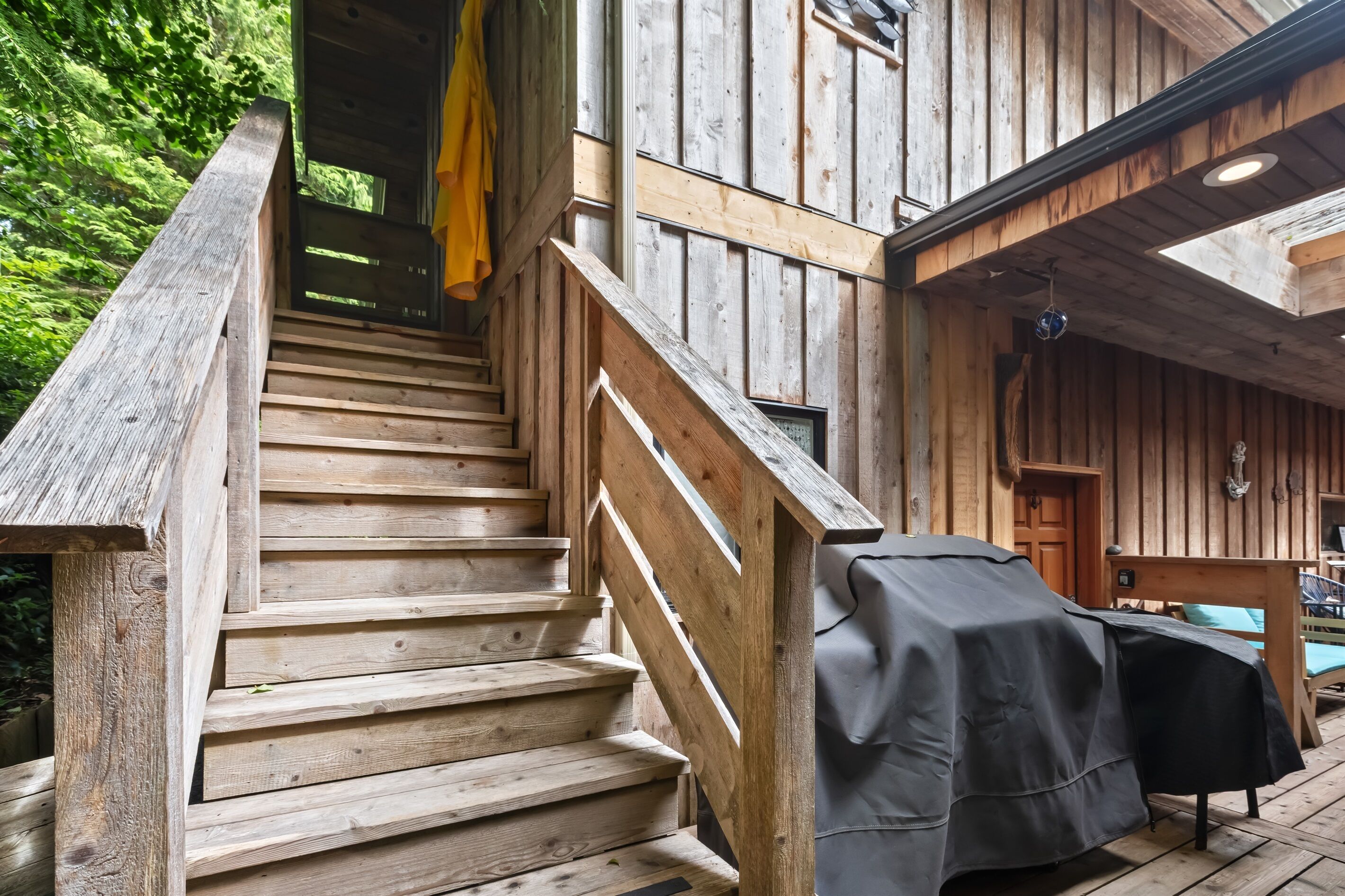 Eine Holztreppe führt zu einer überdachten Außenbereich-Sitzgelegenheit mit Billardtisch.