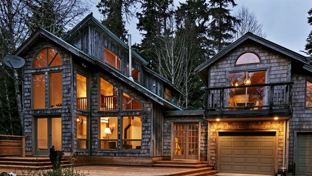 A large, multi-story log cabin with a spacious deck and a garage. - The Crow's Nest Suite - Steps from S. Chesterman (Tofino)