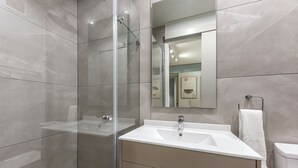 Un bagno moderno con doccia vetrata, lavandino bianco e uno specchio grande.