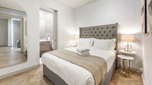 Una moderna camera d'albergo con un letto grande, un comodino, uno specchio e vista sul bagno.