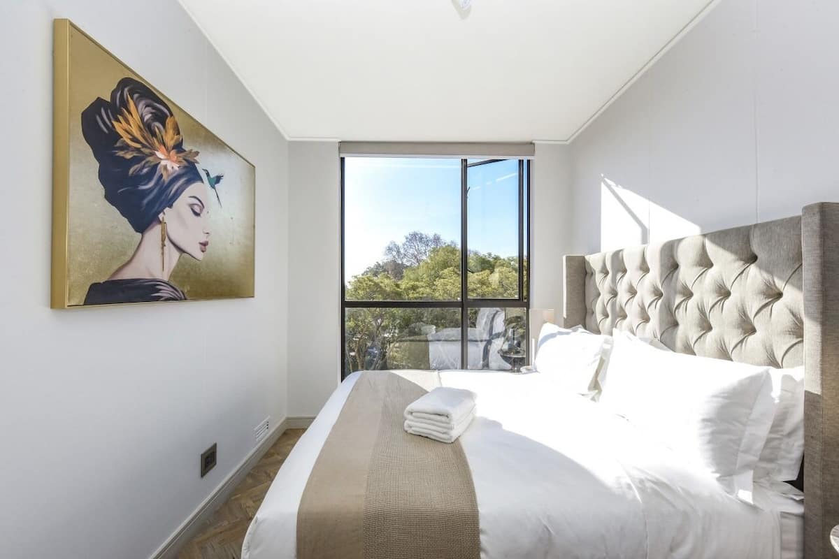 Ein modernes Schlafzimmer mit einem großen Bett, Blick durch eine Schiebetür und einem Bild an der Wand.