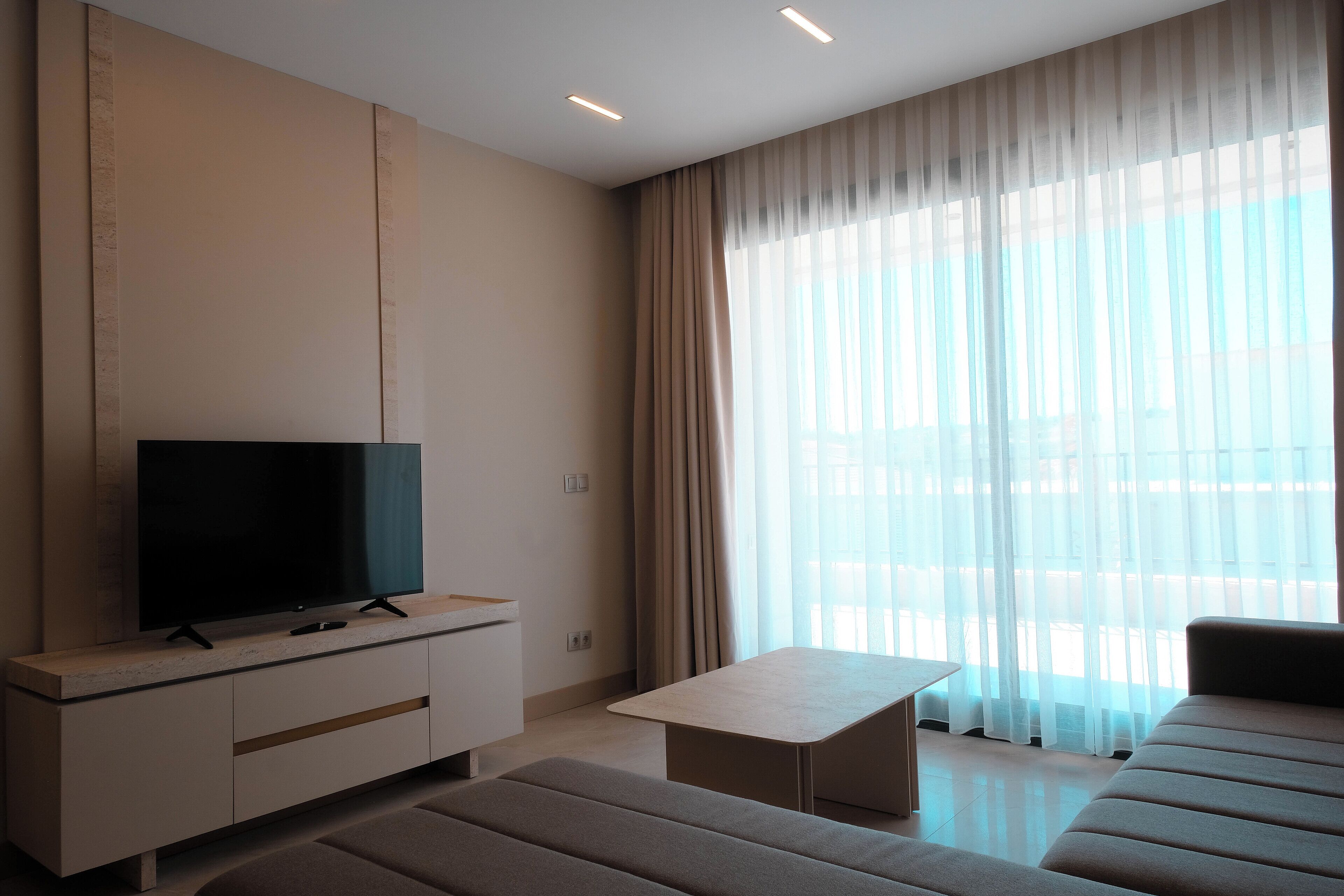 A modern living room with a flat-screen TV on a minimalist console, a sofa, and a coffee table.