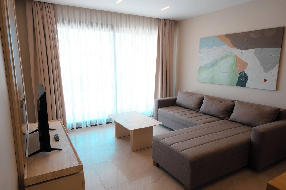 A modern living room with a sofa, a coffee table, and a flat-screen TV on a stand.