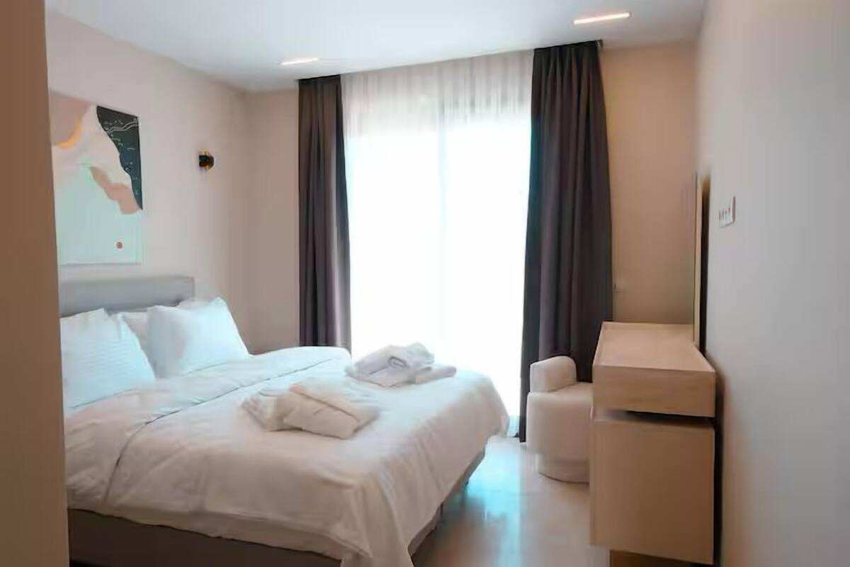 A hotel room with a bed, a desk, and a window with curtains.