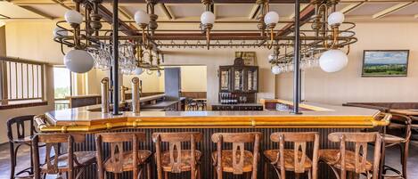A bar area with wooden chairs, a bar counter, and a chandelier with multiple light fixtures.