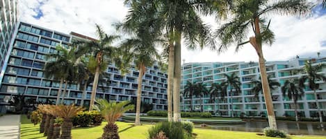 Un hôtel moderne doté d’une cour intérieure, de palmiers et d’un élément décoratif aquatique.