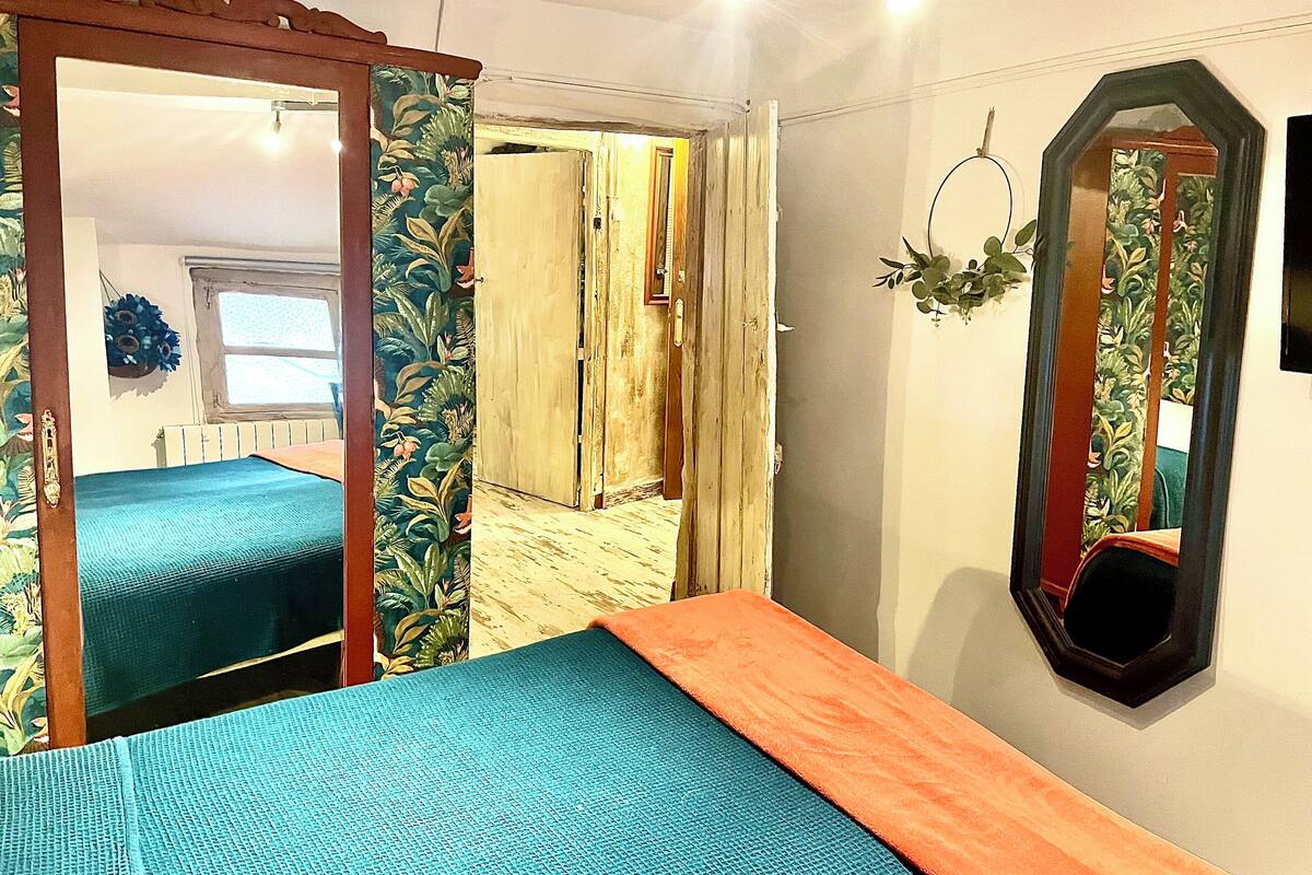 Een kamer met een bed, een spiegel en een deur naar een andere kamer.