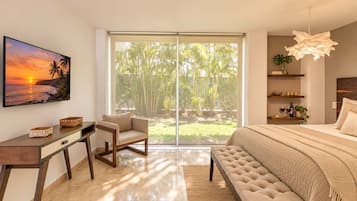 A bedroom with a large bed, a desk, a chair, and a view of a tropical landscape through the sliding doors.