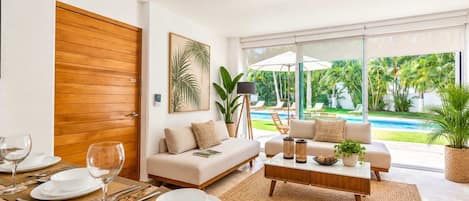 A modern living room with a sofa, coffee table, and dining area set for a meal.