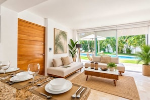 A modern living room with a sofa, coffee table, and dining area set for a meal.