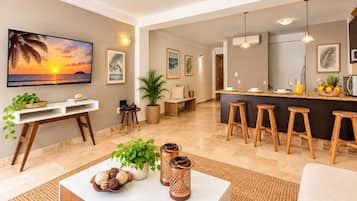 A modern living room with a large TV, a dining area with bar stools, and a kitchen with a bar counter.