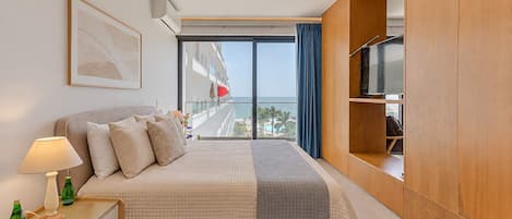 Una habitación de hotel con cama, televisión, mesita de noche y vistas al mar.