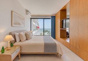 Una habitación de hotel con cama, televisión, mesita de noche y vistas al mar.