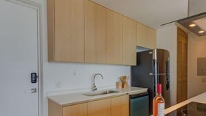 A modern kitchen with wooden cabinets, a stainless steel sink, and a black refrigerator.