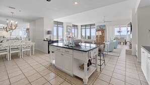A spacious kitchen with a central island, white cabinetry, and large windows. - Summerchase Penthouse 1 (Orange Beach)