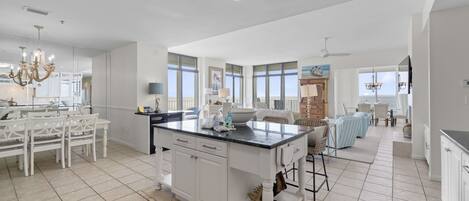 A spacious kitchen with a central island, white cabinetry, and large windows.