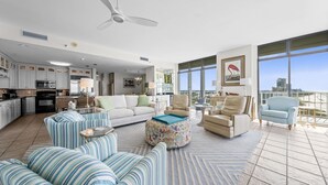 A spacious living area with a kitchen, large windows, and a balcony with a city view. - Summerchase Penthouse 1 (Orange Beach)