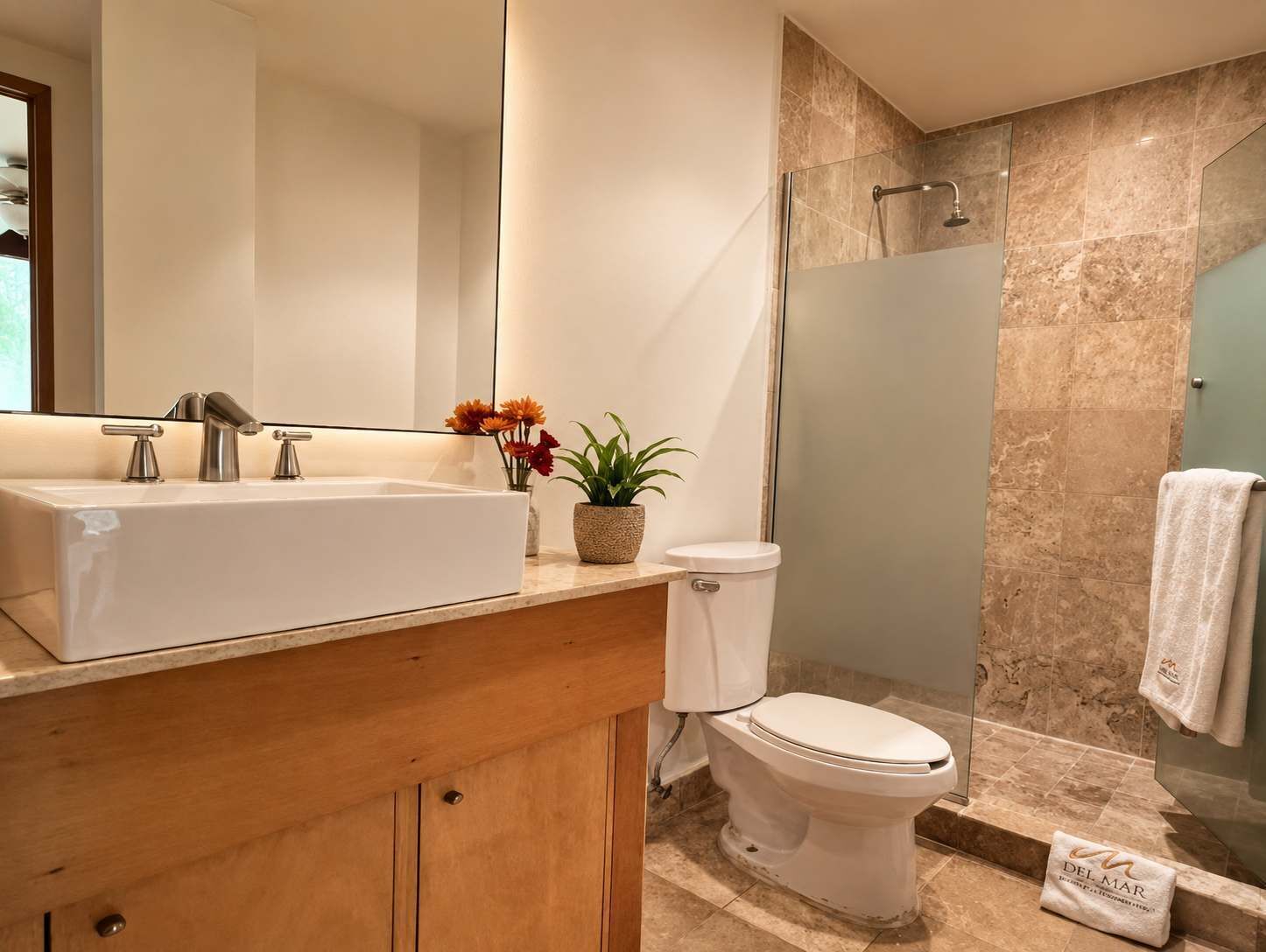 Een badkamer met een wit wastafelmeubel, toilet, douche en spiegel.