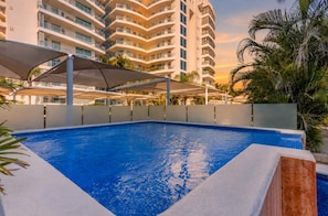 A swimming pool with a clear blue water surface, surrounded by a white pool deck and a white canopy structure. - Pool & Beachfront Stay at Nuevo Vallarta (Bucerías)