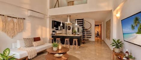 A modern living space with a sofa, coffee table, and a kitchen area with a stove and sink.