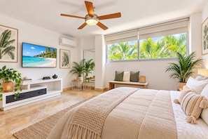 Une chambre moderne avec un lit, un ventilateur de plafond, une télévision et une fenêtre donnant sur des palmiers.