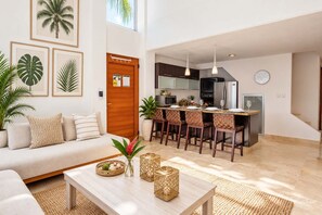 A modern living room with a sofa, coffee table, and artwork on the wall. - Coastal Comfort in Nuevo Vallarta (Bucerías)