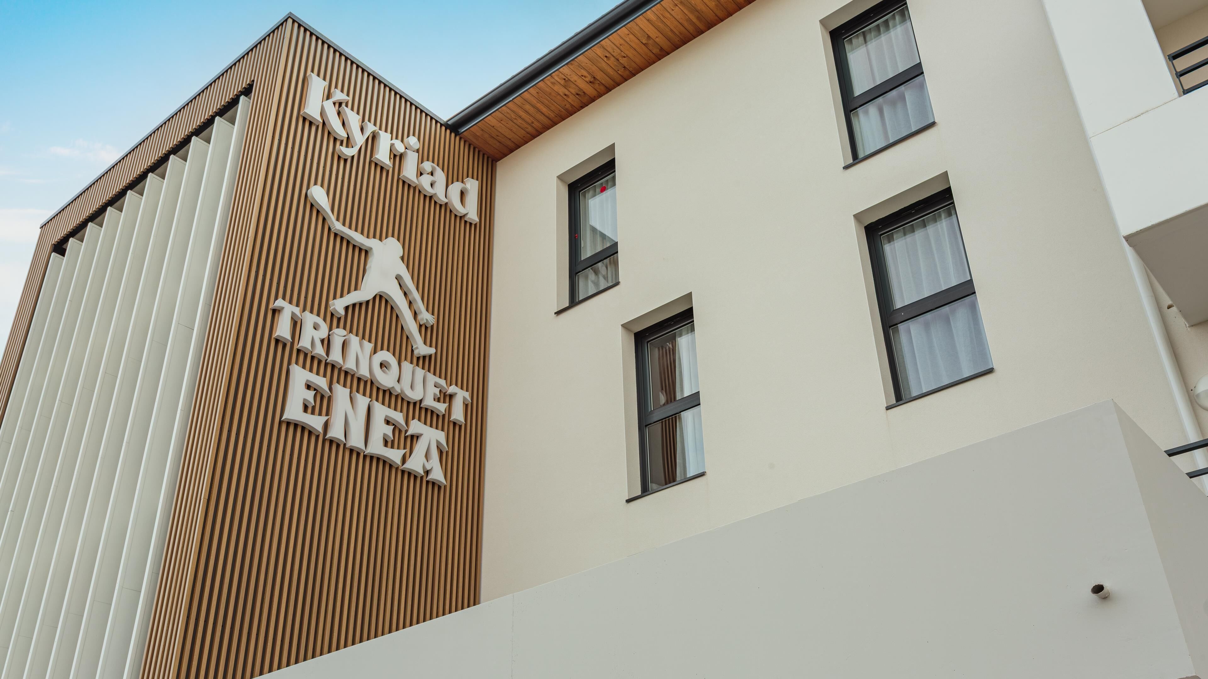 Un edificio con un cartel que dice "Kyriad Trinquet ENEA".